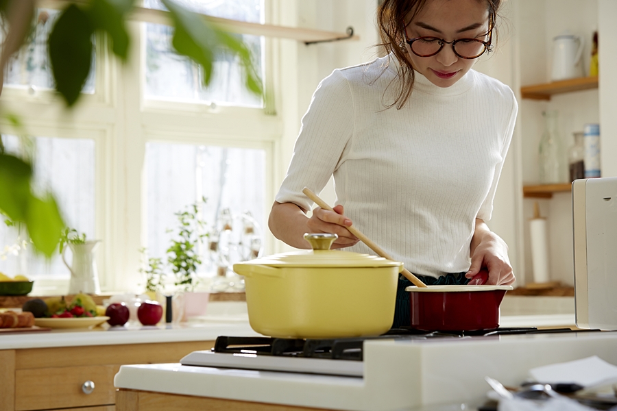 自宅のキッチンで料理を作る若い女性