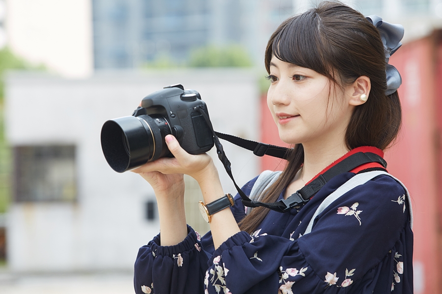 カメラを持って街並みや景色を撮影する若い女性（カメラ女子）